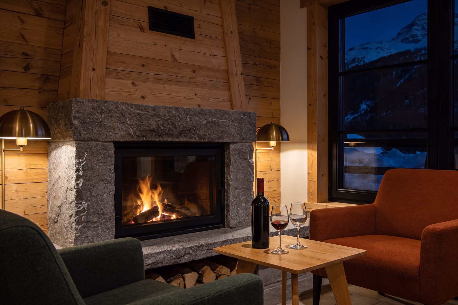 Abendliche Lounge mit offenem Kamin aus Granit und Wollsesseln